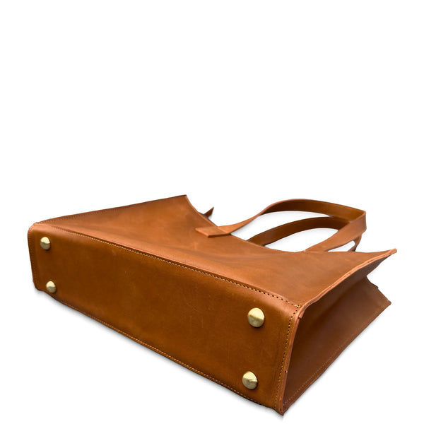 Brown leather tote bag with gold studs on a white background