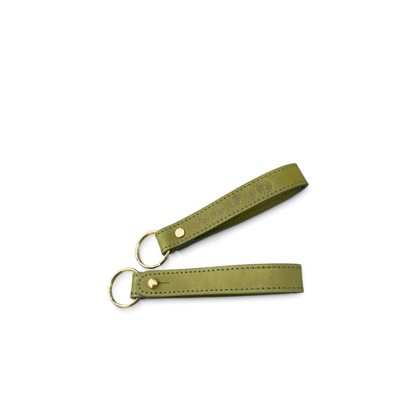 Two green leather keychains on a white background