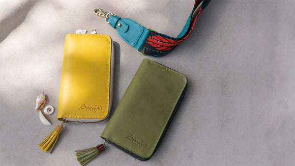 Two leather wallets, one yellow and one green, with colorful straps on a gray background.