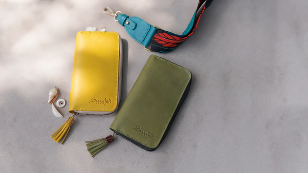 Two small leather bags, one yellow and one green, on a light gray surface.