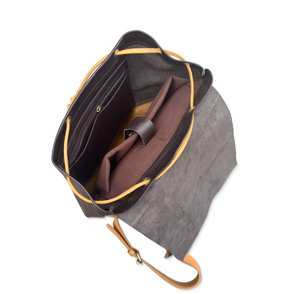 Angled top view of open two-tone leather backpack, with inner compartments, zip pocket, and rolled pouch