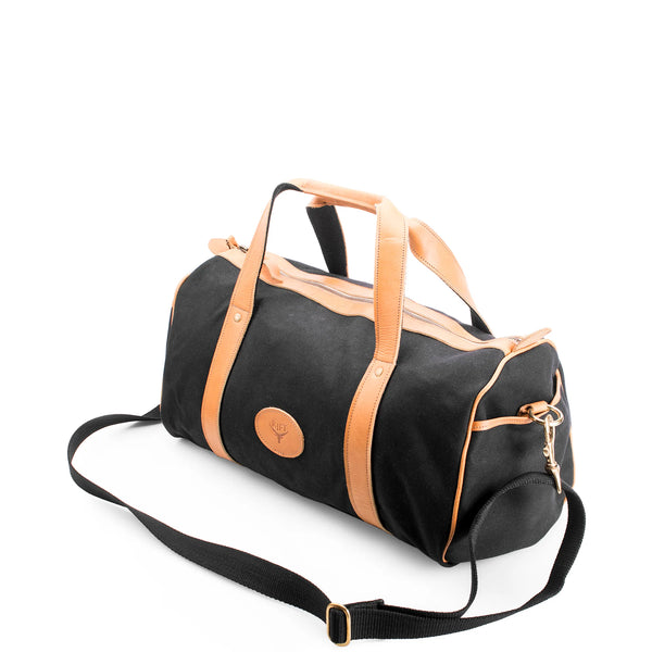 Black duffel bag with tan handles and accents on a white background