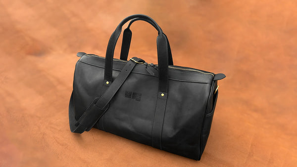 Black duffel bag on a brown leather surface