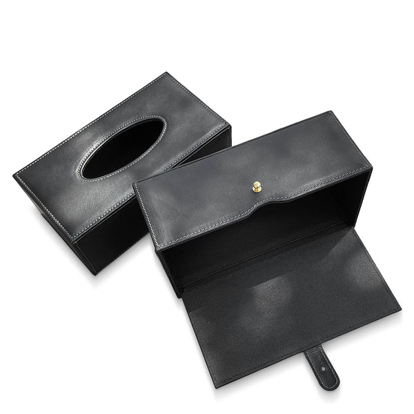 Black leather tissue box cover with a gold button on a white background