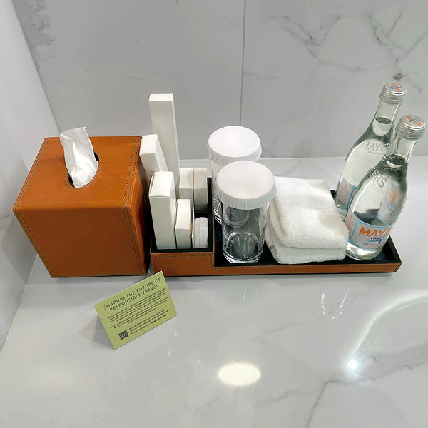 Bathroom counter with toiletries including bottles, cups, and a towel on a white marble surface.