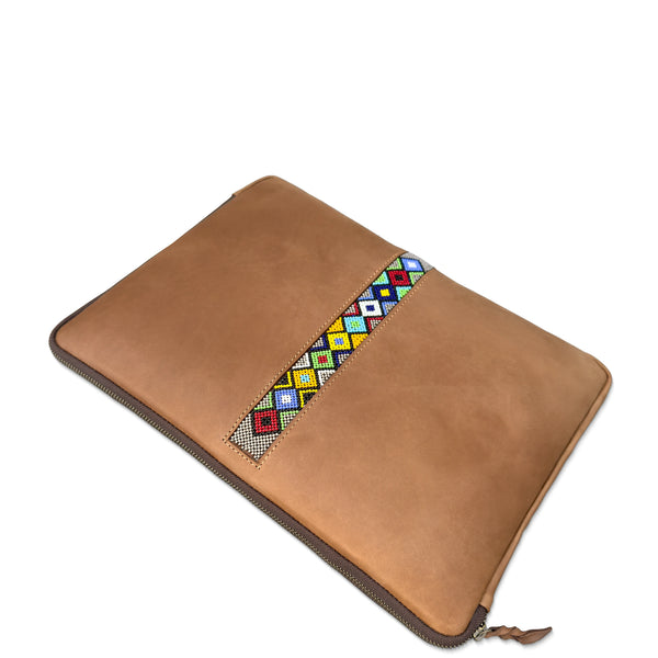 A tan leather laptop sleeve with a colorful geometric beaded pattern strip across the front, shown on a plain white background.