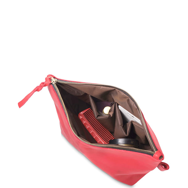 Red makeup bag with a comb and other items on a white background