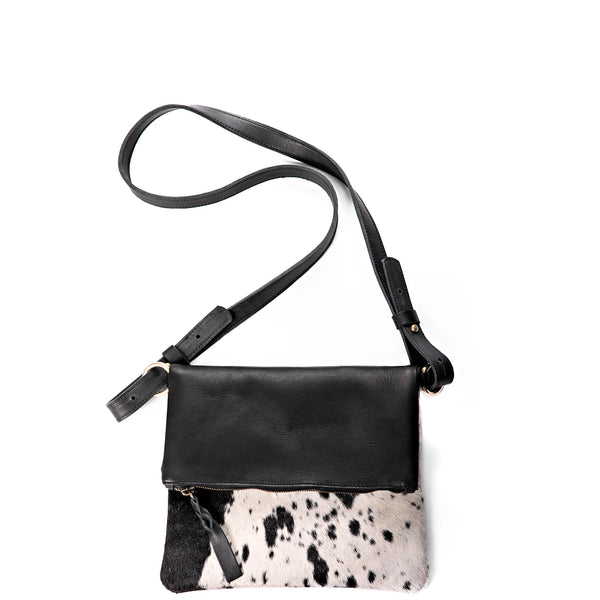 Black leather crossbody bag with cow print panel on a white background
