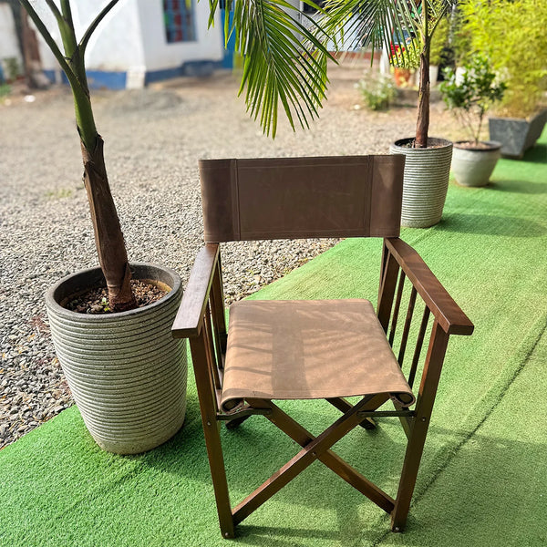 leather and wooden chair on a green grass surface with potted plants in the background.