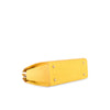 Yellow leather handbag with crocodile texture on a white background