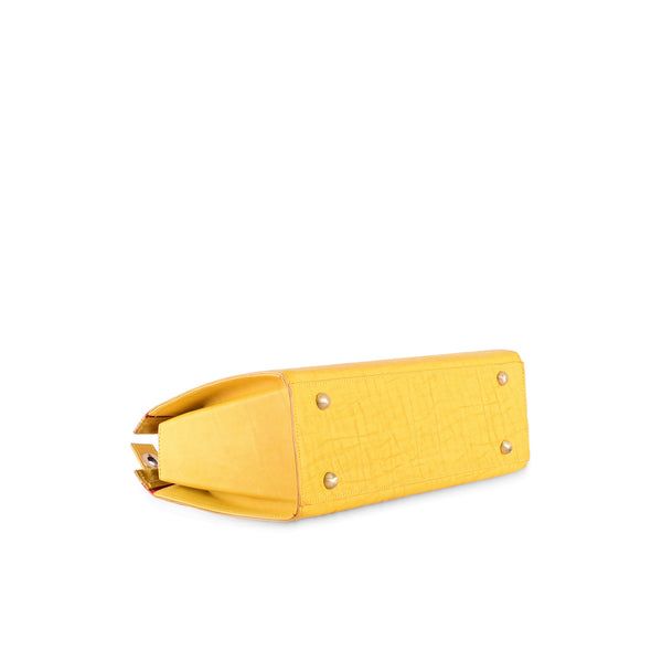 Yellow leather handbag with crocodile texture on a white background