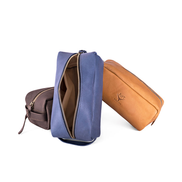 Three leather toiletry bags in different colours on a white background