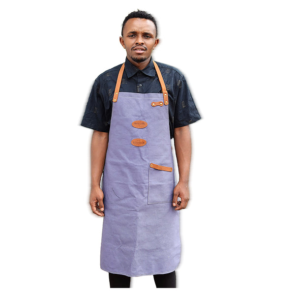 Person wearing a blue apron with brown leather accents on a white background