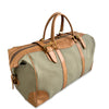 Green duffel bag with brown leather straps and handles on a white background