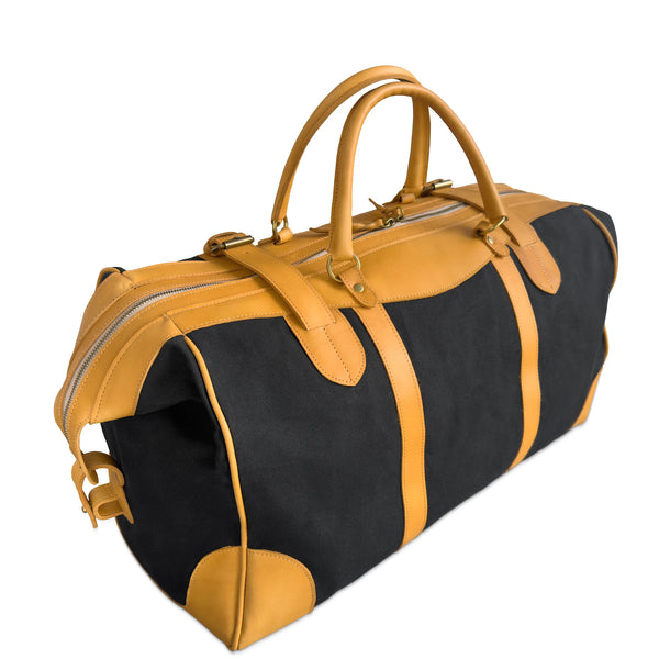 A black and mustard yellow duffel bag with dual top handles, buckle straps, and a zip-around closure, photographed on a clean white background.