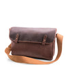 Brown leather satchel bag with a strap on a white background
