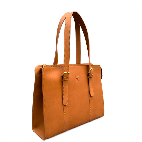 A tan leather tote bag with dual shoulder straps, gold-tone buckle details, and a small embossed logo on the front, shown on a plain white background.