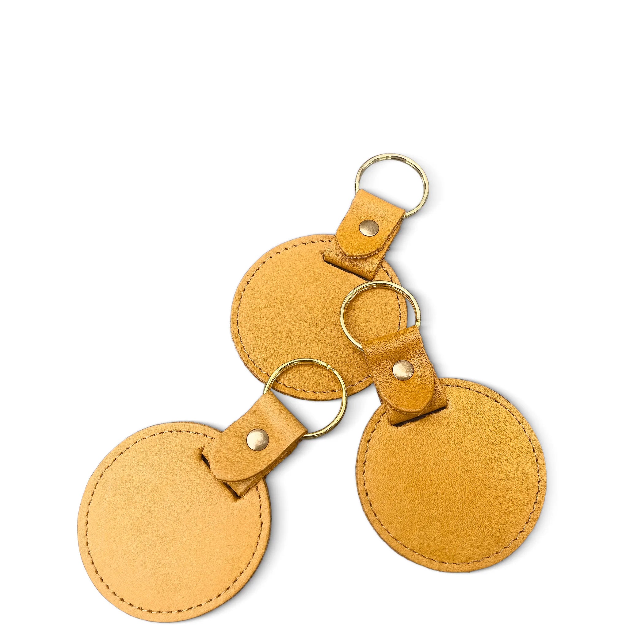 Three tan leather keychains with gold rings on a white background