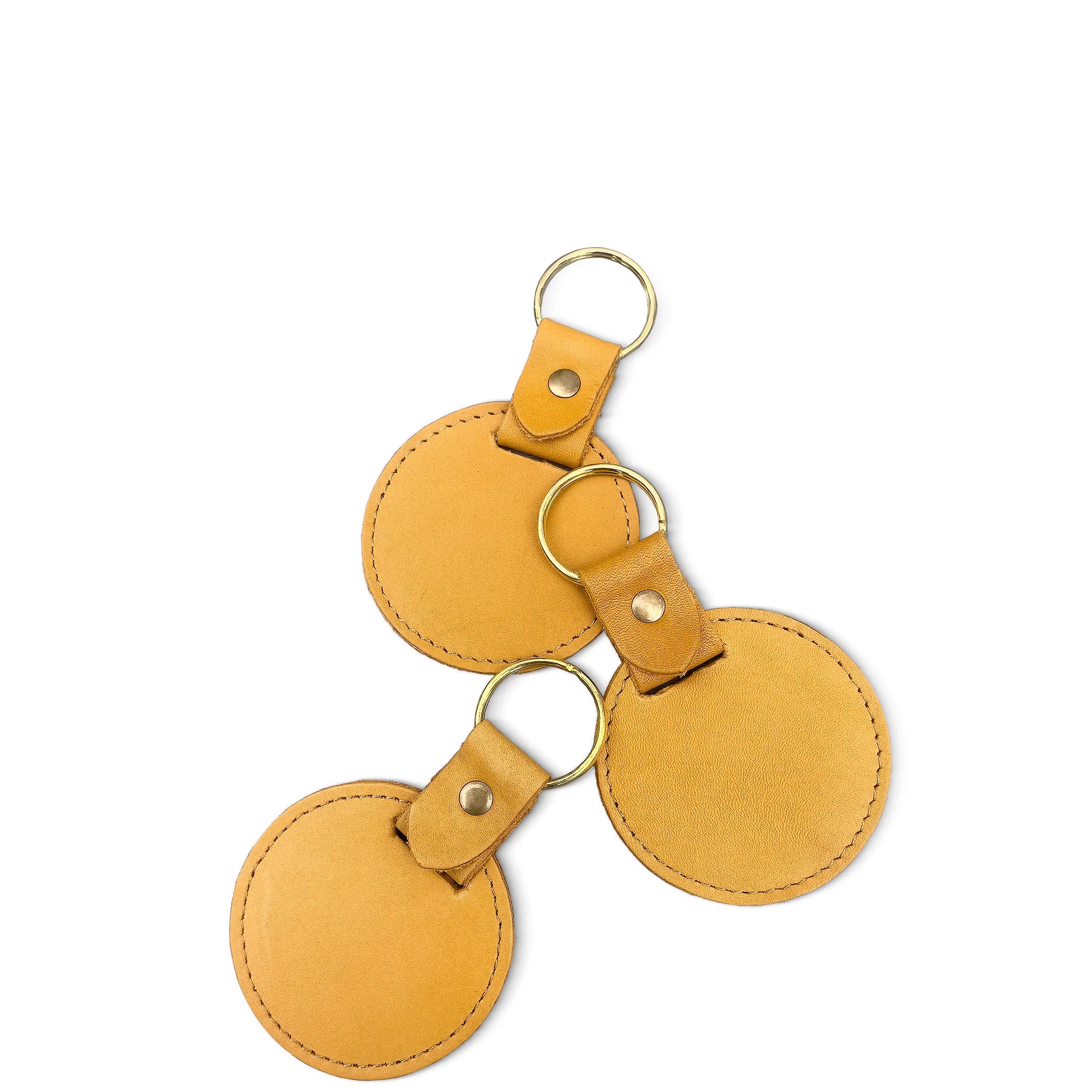 Three yellow leather keychains with gold rings on a white background