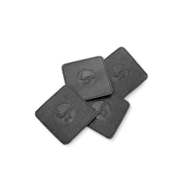 Four black leather coasters with a logo on a white background