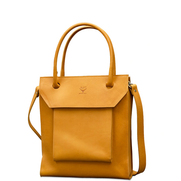 A tan leather tote bag with a front flap pocket, dual top handles, and a detachable shoulder strap, shown on a plain white background.