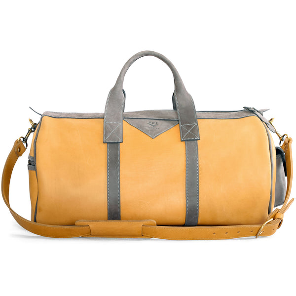Tan leather duffel bag with gray straps on a white background