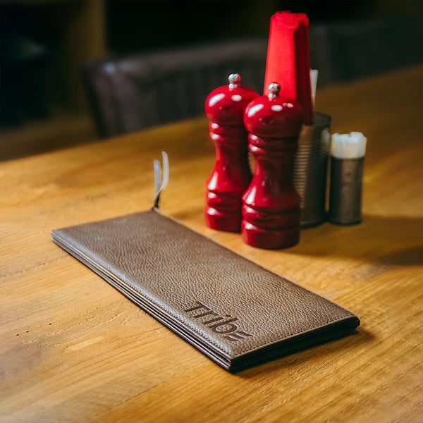 Brown leather wallet with 'Tide' branding on a wooden table with red salt and pepper shakers.