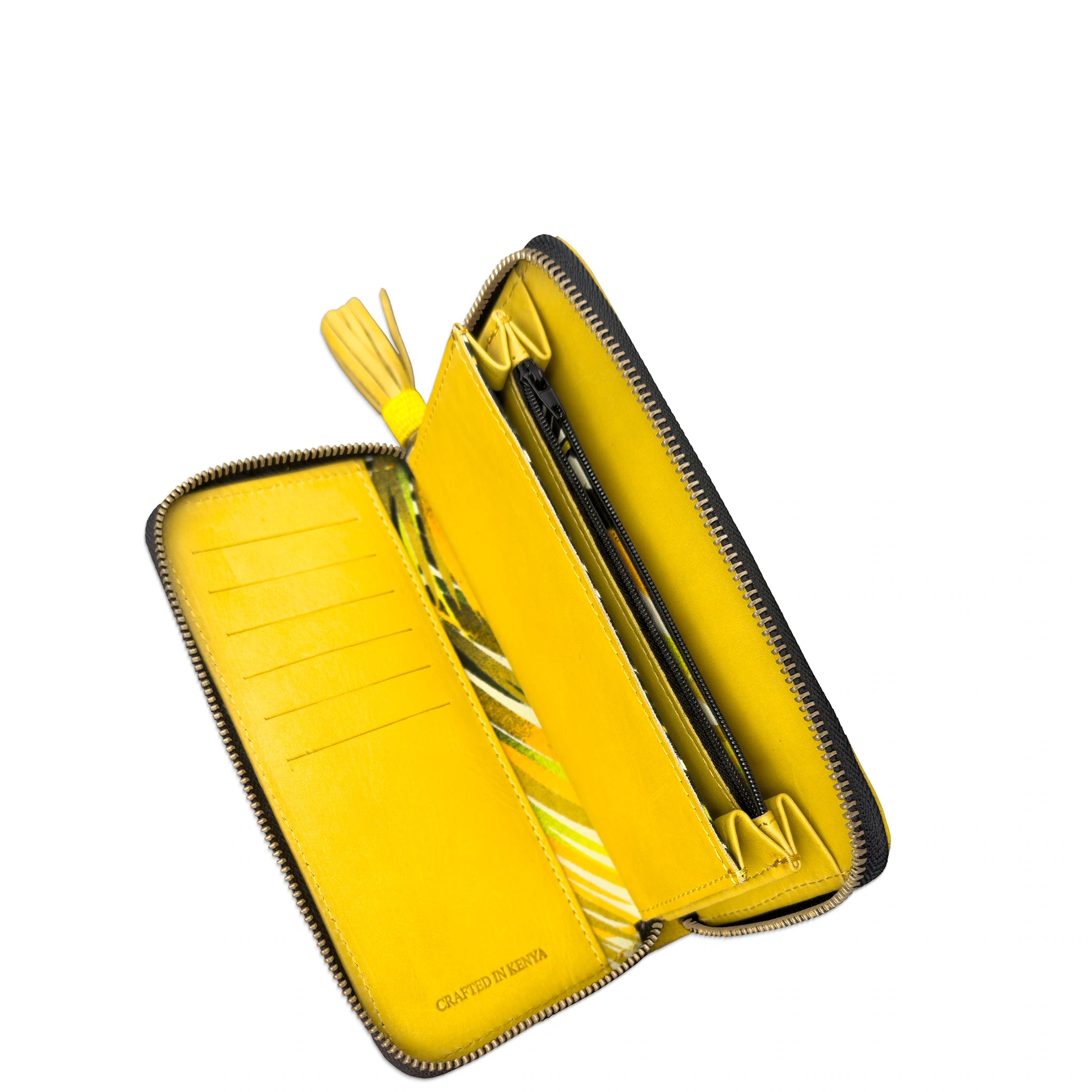 A bright yellow leather zip-around wallet shown open, revealing multiple card slots, a pen loop, and a tassel detail. The brand name 'CRAFTED IN DENMARK' is subtly printed on the bottom interior corner.