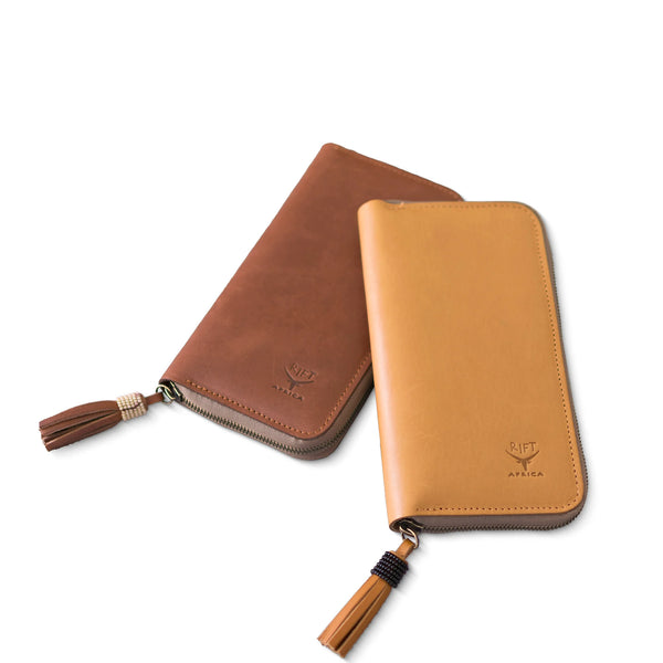 Two brown leather wallets with tassels on a white background