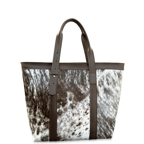 Tote bag with cow print pattern and brown straps on a white background