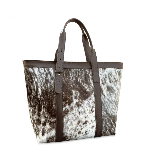 Tote bag with cow print pattern and brown leather straps on a white background