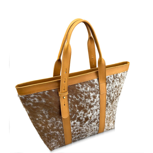 Tote bag with cowhide pattern and tan handles on a white background